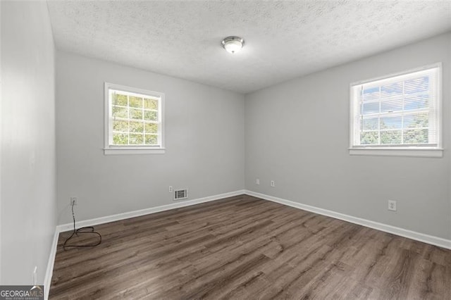 unfurnished room with dark wood finished floors, baseboards, and visible vents