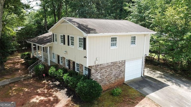 view of property exterior with an attached garage, brick siding, and driveway