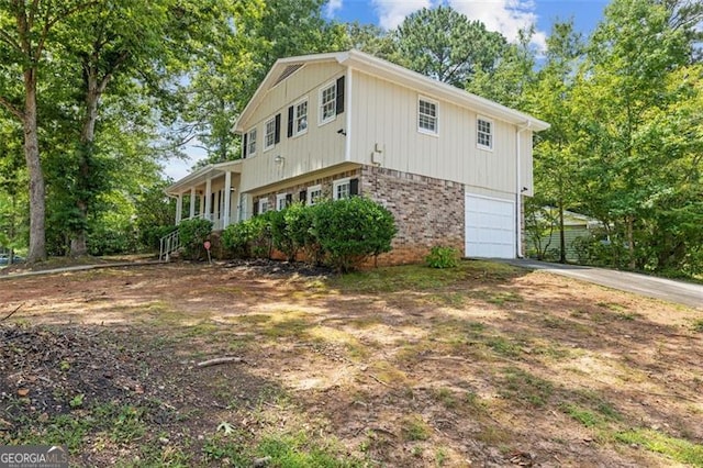 view of side of property featuring a garage, brick siding, and driveway