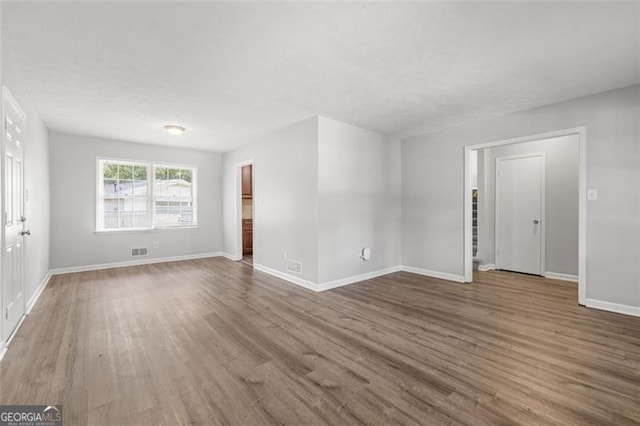 interior space featuring visible vents, baseboards, a textured ceiling, and wood finished floors