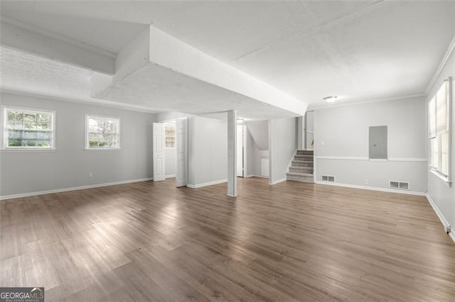 unfurnished living room with visible vents, wood finished floors, and stairway