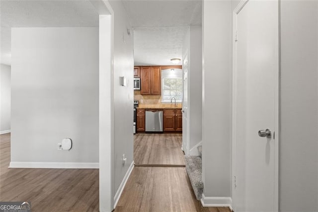 hall featuring a sink, baseboards, wood finished floors, and stairs