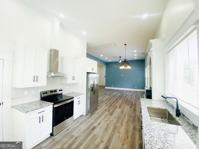 kitchen with white cabinets, sink, wall chimney exhaust hood, decorative light fixtures, and stainless steel appliances