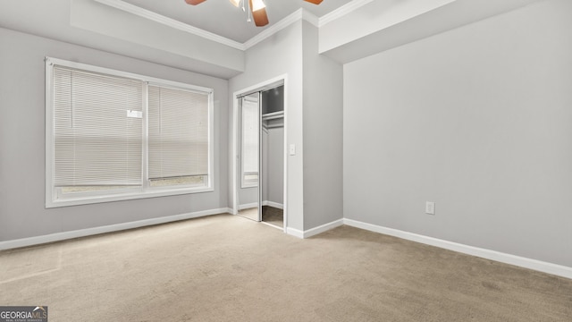 unfurnished bedroom with crown molding, ceiling fan, a closet, and light colored carpet