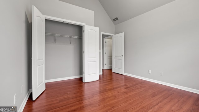 unfurnished bedroom featuring dark hardwood / wood-style floors, high vaulted ceiling, and a closet