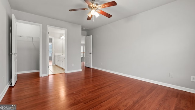 unfurnished bedroom with a walk in closet, ensuite bath, ceiling fan, light hardwood / wood-style floors, and a closet