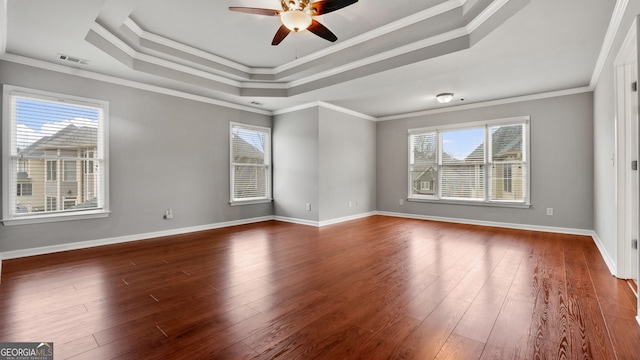 empty room featuring a raised ceiling, crown molding, plenty of natural light, and dark hardwood / wood-style floors