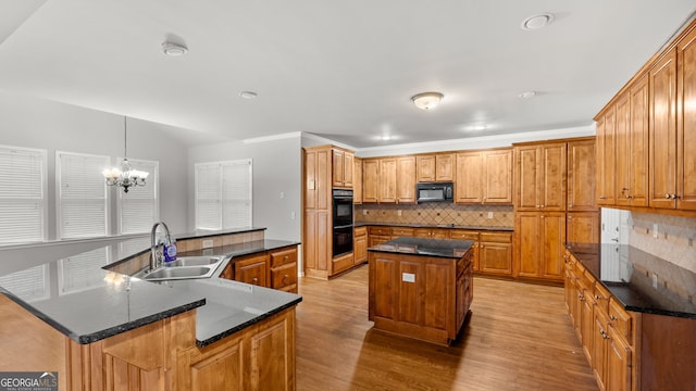 kitchen featuring a center island, sink, pendant lighting, a chandelier, and black appliances