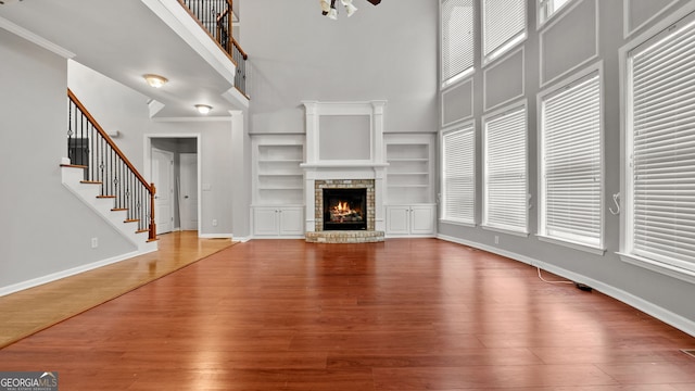 unfurnished living room with hardwood / wood-style floors, ornamental molding, a fireplace, and a wealth of natural light