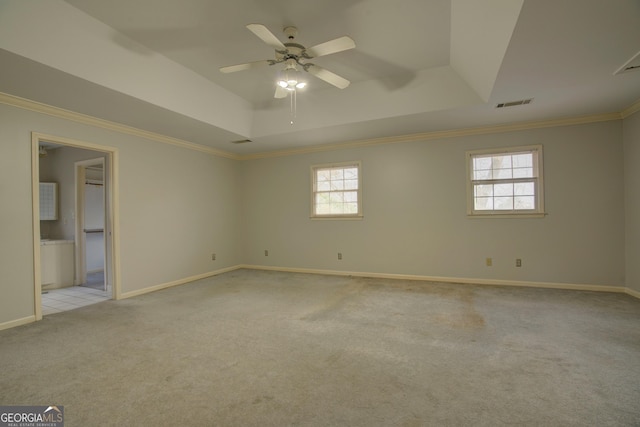 carpeted empty room featuring a raised ceiling, crown molding, and ceiling fan