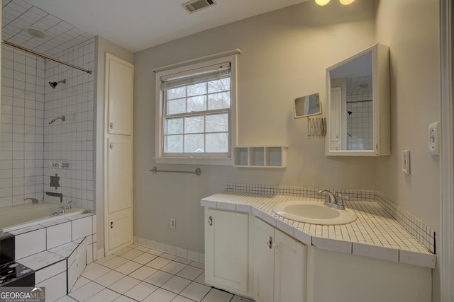 bathroom featuring vanity, tile patterned flooring, and tiled shower / bath