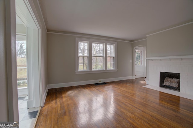 unfurnished living room featuring crown molding, dark hardwood / wood-style flooring, and a brick fireplace