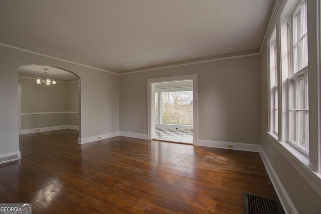 spare room with dark wood-type flooring, crown molding, and an inviting chandelier