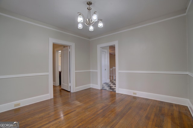 spare room with dark wood-type flooring, ornamental molding, and a chandelier