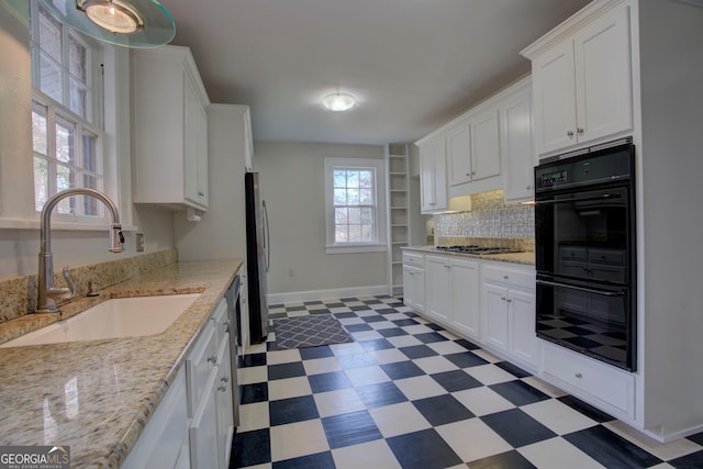 kitchen featuring appliances with stainless steel finishes, tasteful backsplash, white cabinetry, sink, and light stone counters