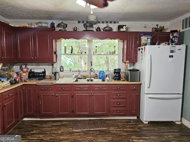 kitchen with sink, dark wood-type flooring, white refrigerator, and a textured ceiling