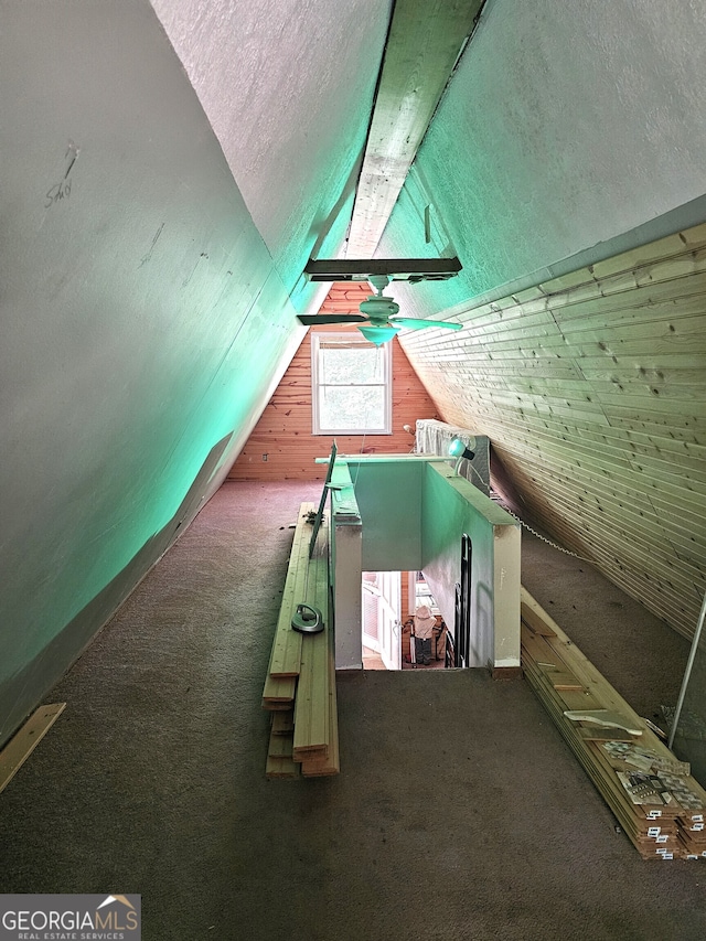 additional living space with wood walls, carpet flooring, vaulted ceiling, and a textured ceiling