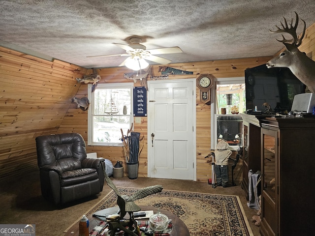 sitting room featuring plenty of natural light, lofted ceiling, wooden walls, and carpet flooring