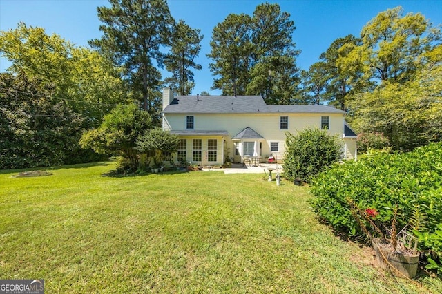 back of house with a chimney, a yard, and a patio area
