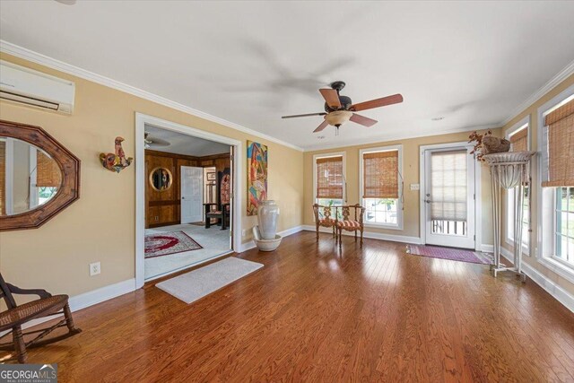 unfurnished living room featuring baseboards, ornamental molding, a ceiling fan, and an AC wall unit