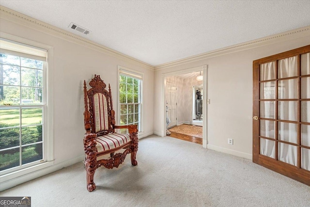 living area featuring carpet floors, ornamental molding, baseboards, visible vents, and a textured ceiling