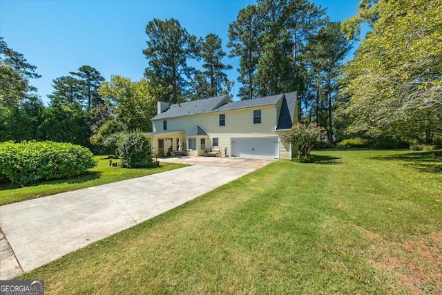 back of property with concrete driveway, a yard, and an attached garage