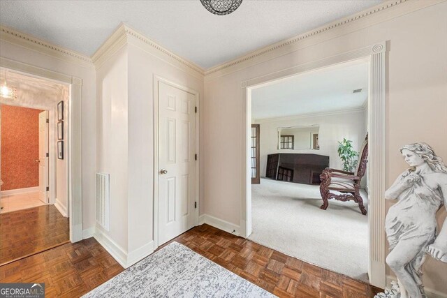 hall featuring baseboards, visible vents, and ornamental molding