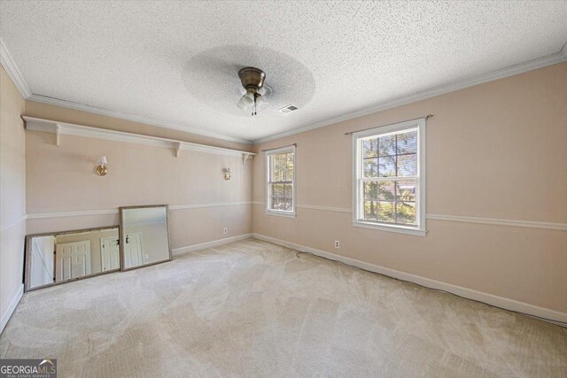 spare room with ornamental molding, baseboards, visible vents, a ceiling fan, and a textured ceiling