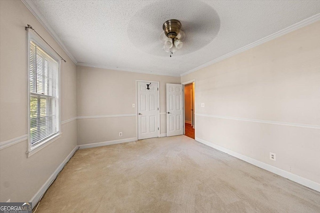 carpeted spare room featuring a textured ceiling, ceiling fan, ornamental molding, and baseboards