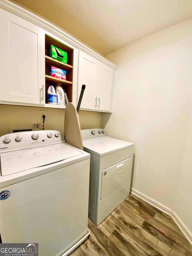 laundry area featuring hardwood / wood-style flooring, washer and dryer, and cabinets