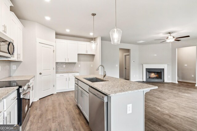 kitchen featuring pendant lighting, sink, an island with sink, appliances with stainless steel finishes, and white cabinetry