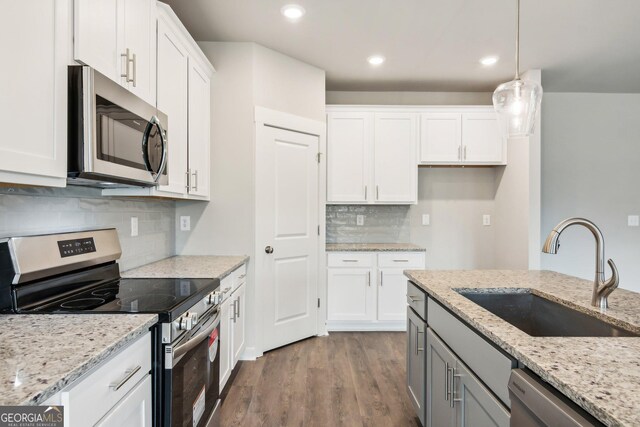 kitchen featuring white cabinetry, sink, hanging light fixtures, stainless steel appliances, and light stone counters