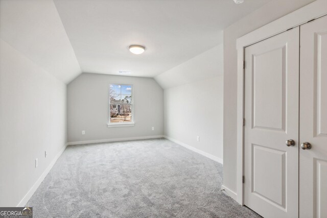 bonus room with light colored carpet and lofted ceiling