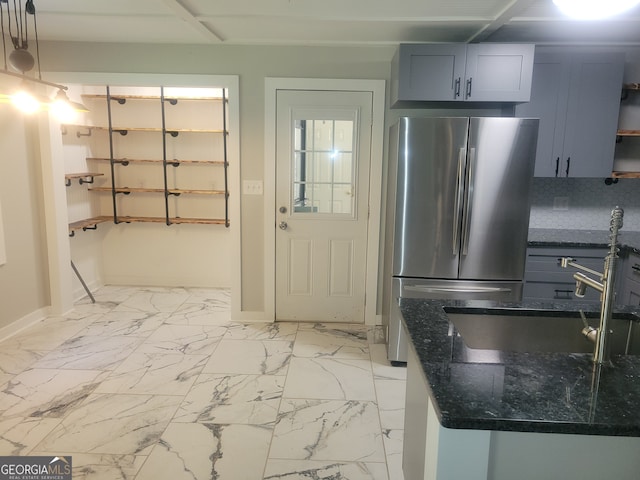 kitchen with tasteful backsplash, stainless steel refrigerator, light tile patterned floors, dark stone countertops, and hanging light fixtures