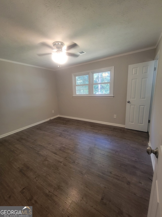 empty room featuring ceiling fan, a textured ceiling, dark wood-type flooring, and ornamental molding