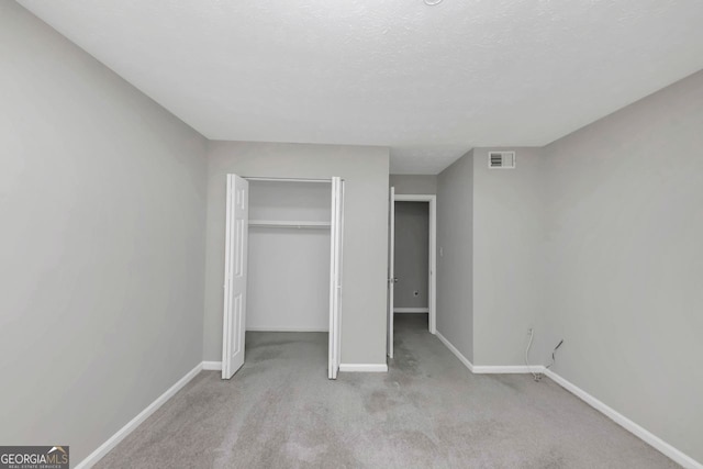 unfurnished bedroom featuring a closet, light carpet, and a textured ceiling