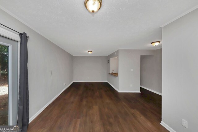 interior space with a textured ceiling, dark wood-type flooring, and crown molding