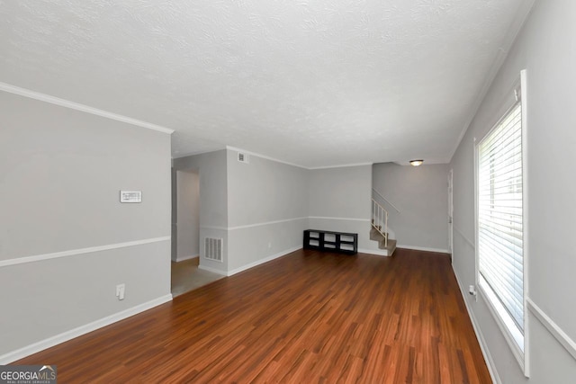 unfurnished living room featuring a textured ceiling, dark hardwood / wood-style floors, and ornamental molding