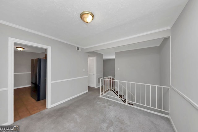 carpeted empty room featuring a textured ceiling and ornamental molding