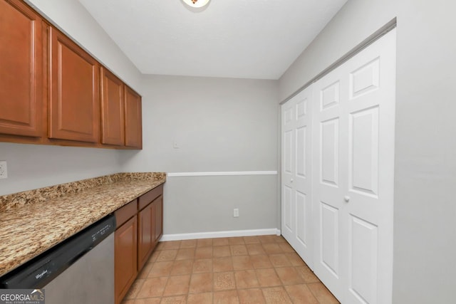 kitchen featuring light stone counters, dishwasher, and light tile patterned floors