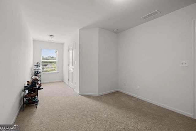 hallway with light carpet, visible vents, and baseboards