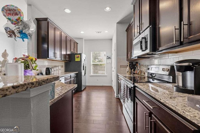 kitchen featuring dark brown cabinetry, appliances with stainless steel finishes, backsplash, and light stone counters