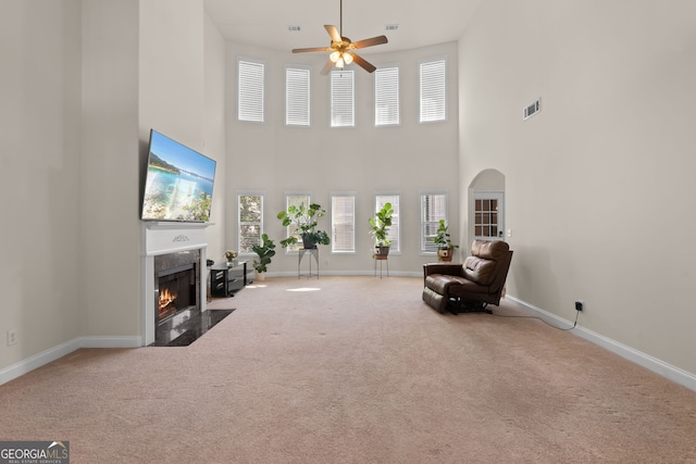 unfurnished room with a high ceiling, ceiling fan, and carpet