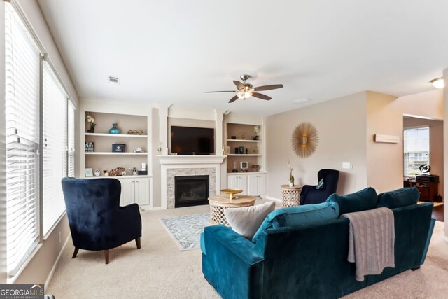 carpeted living room featuring built in shelves and ceiling fan