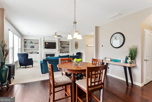 dining room with built in features, dark hardwood / wood-style floors, and ceiling fan with notable chandelier