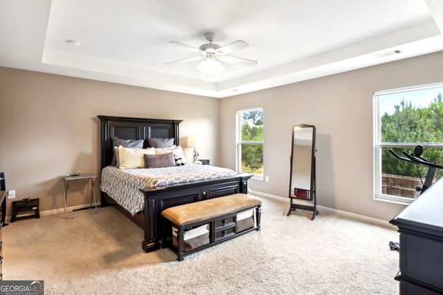 carpeted bedroom with a tray ceiling and ceiling fan