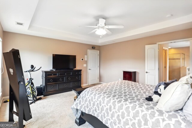 carpeted bedroom with ceiling fan and a raised ceiling