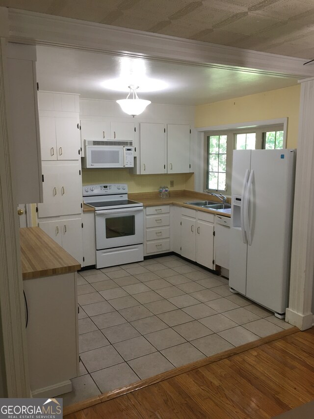 kitchen featuring white appliances, light hardwood / wood-style flooring, sink, ornamental molding, and white cabinetry