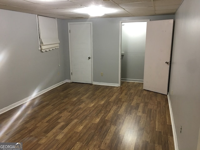 interior space featuring a paneled ceiling and dark hardwood / wood-style floors