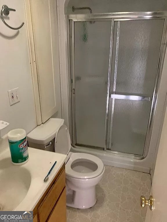 bathroom with a shower with door, tile patterned floors, vanity, and toilet